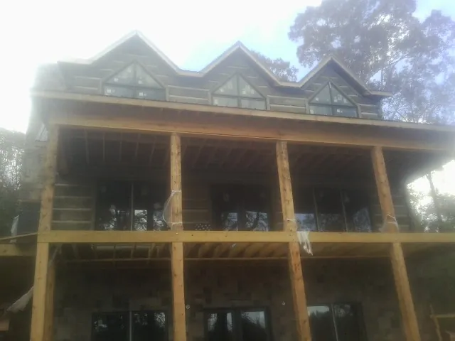 Dormers and porch framing on a large log home under construction — Roof Coating work by our crew in White City