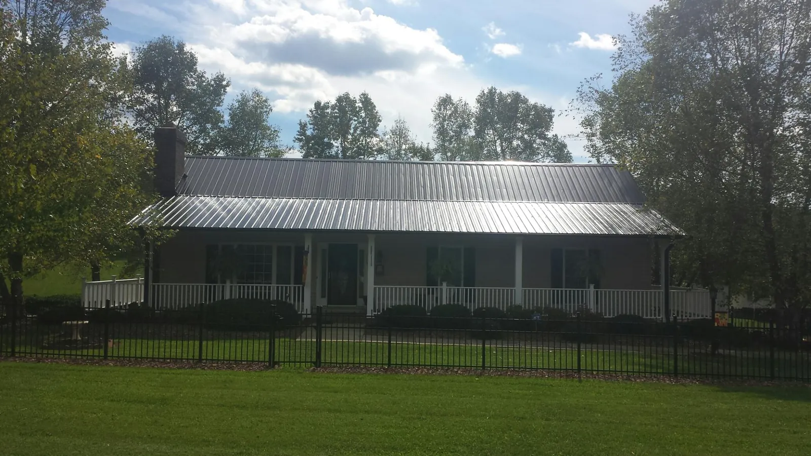 Gray metal roof on a brick ranch with a full width front porch — Gutter Guard Installation work by our crew in White City